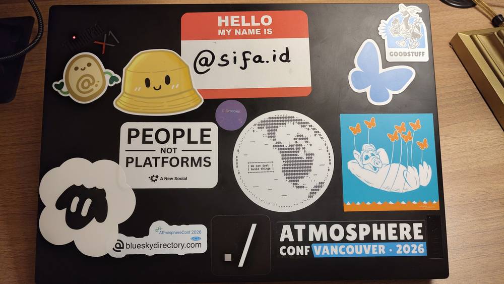 A conference badge and sticker sheet reading "Hello my name is @sifa.id", alongside "People Not Platforms" and AtmosphereConf Vancouver 2026 stickers.