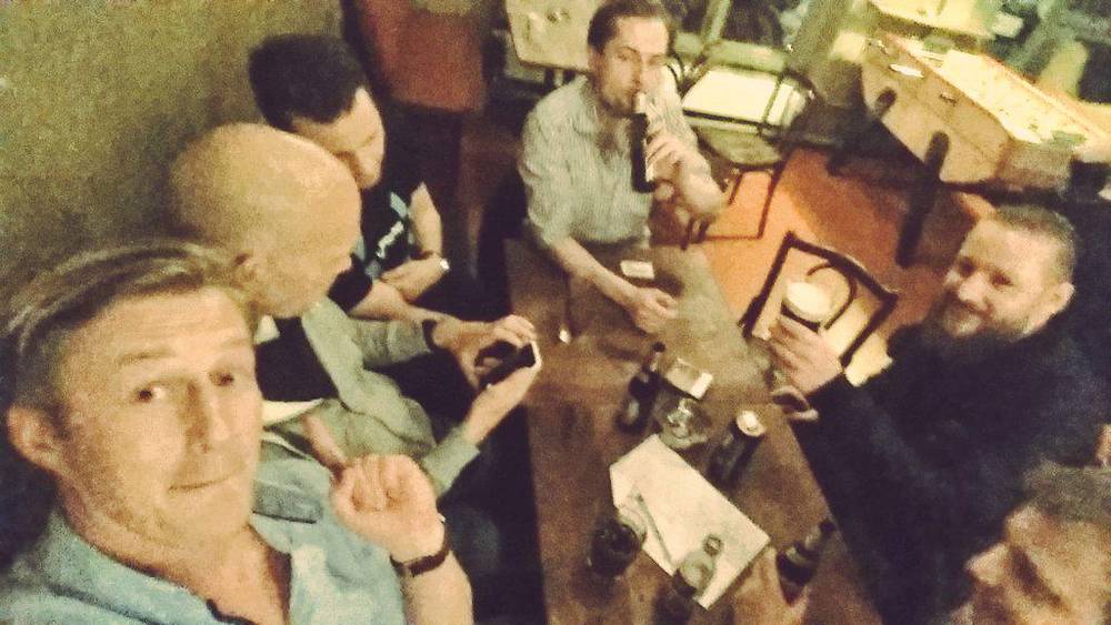 A vintage-filtered photo of men drinking together at a late-night afterparty.