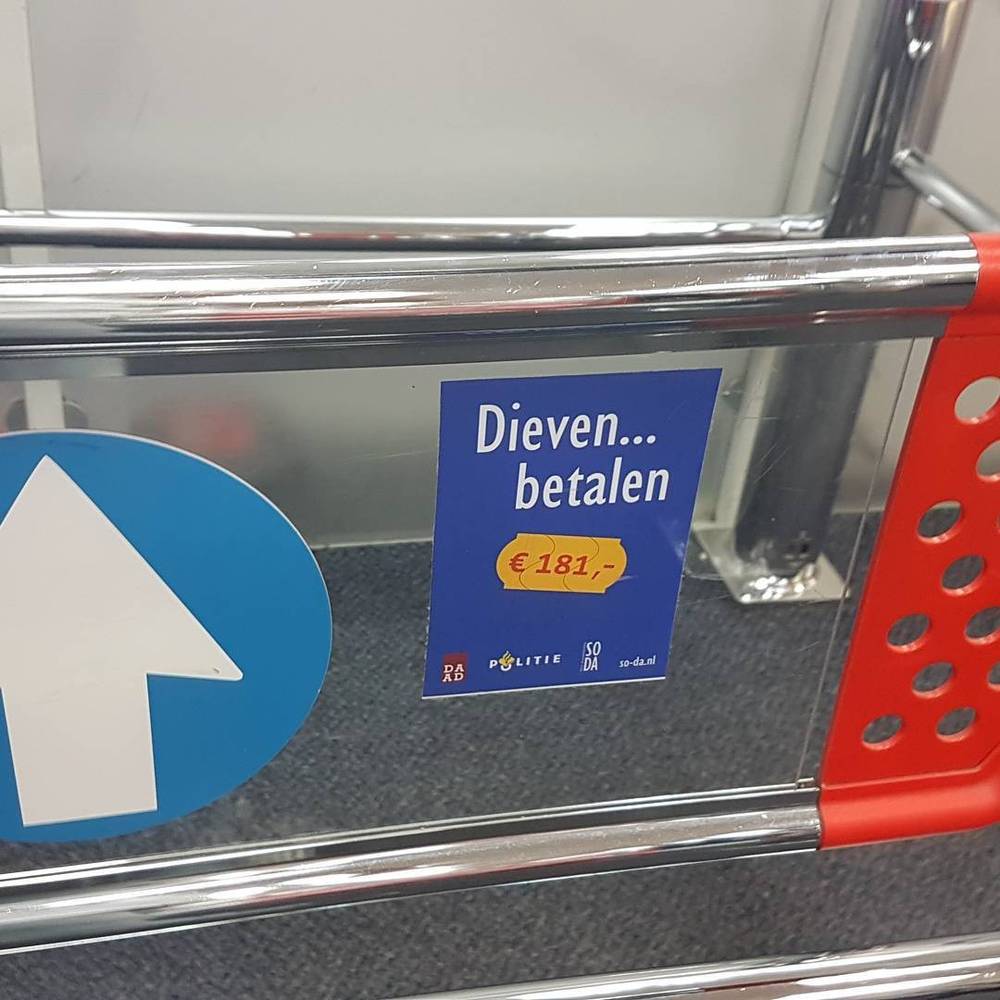 A shopping cart handle with a sticker warning "Thieves pay €181" in Dutch.