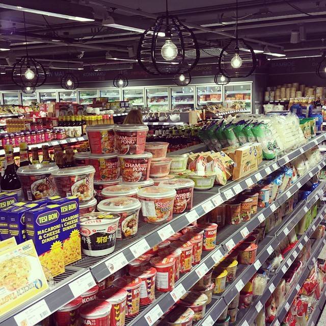Rows of packaged food products on shelves inside a well-lit Asian supermarket.