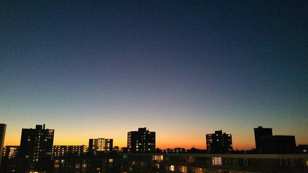 Silhouetted apartment buildings against a colorful sunset sky.