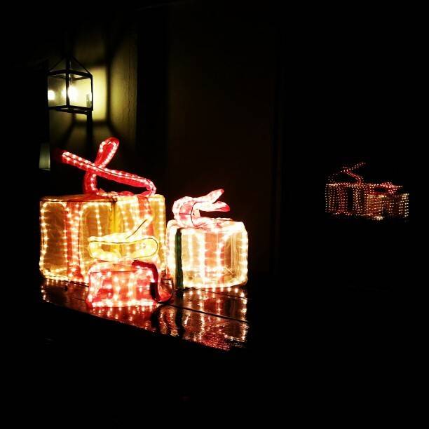 Illuminated string-light gift box decorations glowing in the dark near an entrance.