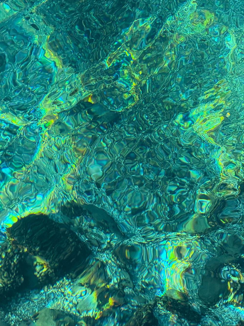 Water at Lake Geneva — incredibly clear, to the extent that it reflects light almost like a jewel, with emeralds and blues shining through. 