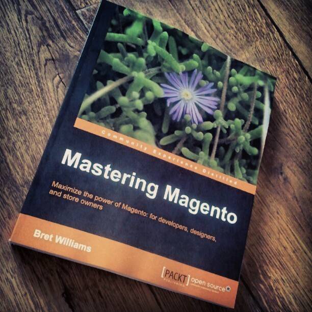 The book 'Mastering Magento' by Bret Williams lying on a wooden table.