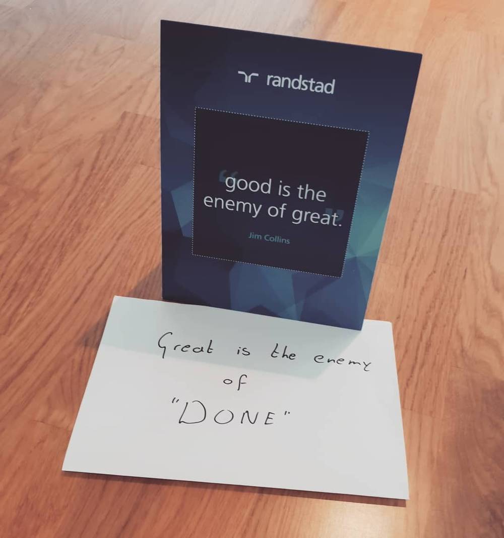 A Randstad branded card with the quote 'good is the enemy of great', next to a handwritten note reading 'Great is the enemy of Done'.