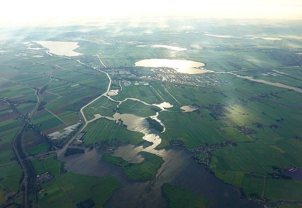Aerial view of Dutch farmland and lakes, seen from a descending airplane.