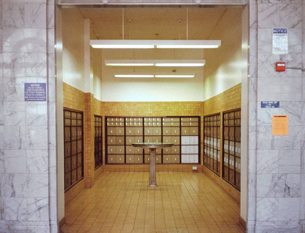 A room of PO boxes with a small green glass table and fluorescent lighting