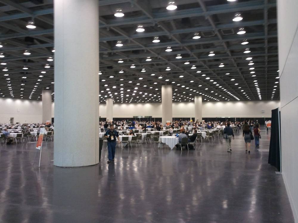 Round tables fill a vast, mostly empty exhibition hall during breakfast hours.