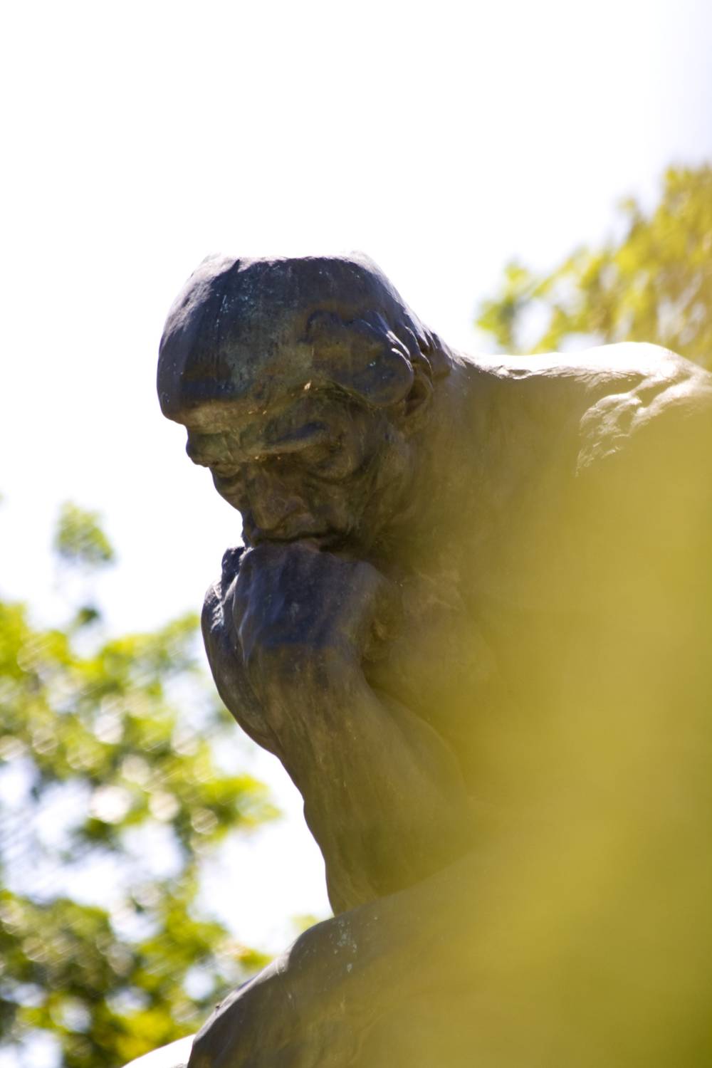 A close-up shows the furrowed brow and clenched hand of Rodin's 'The Thinker'.