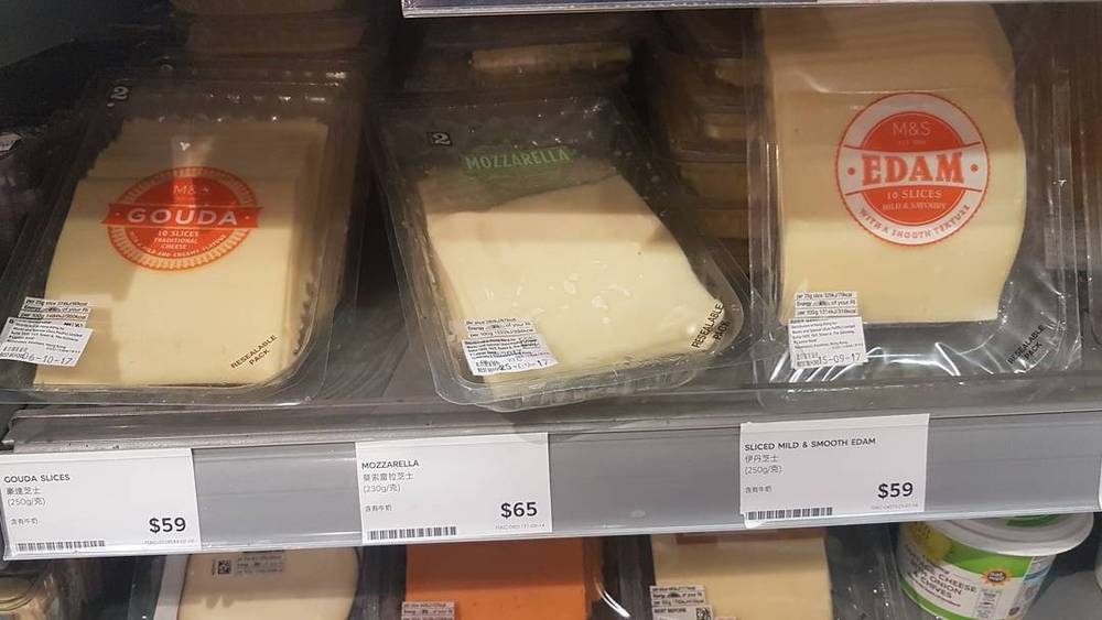 Packaged cheese slices, mozzarella and Edam, on a supermarket shelf with price tags in Hong Kong dollars.