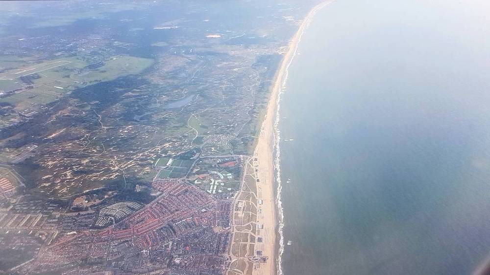 Aerial view of a coastline where a town meets a sandy beach and the sea.