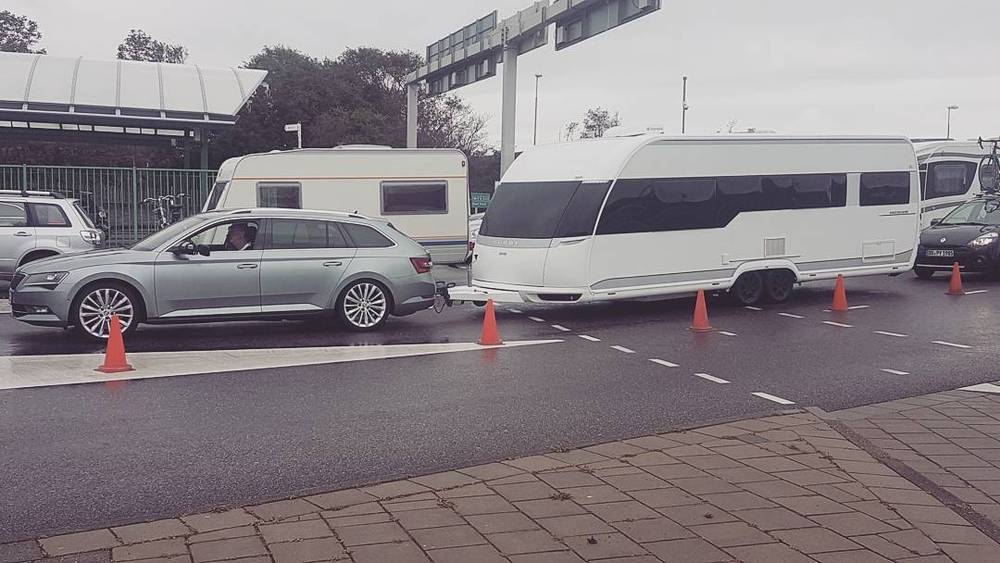 Cars and caravans queuing at a ferry terminal.