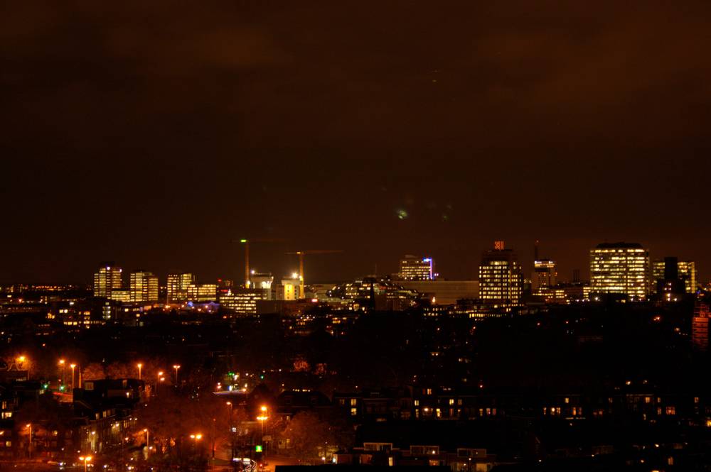 A wide night view of the Utrecht skyline with a cluster of lit office buildings.