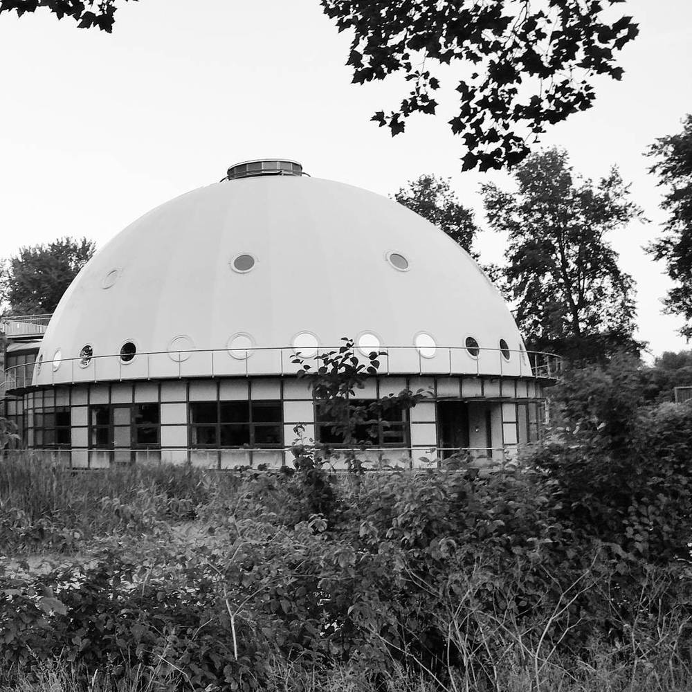 A black-and-white photo of a domed planetarium building surrounded by trees.