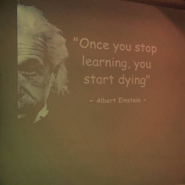 A projected quote reading '"Once you stop learning, you start dying" ~ Albert Einstein' with a portrait illustration.