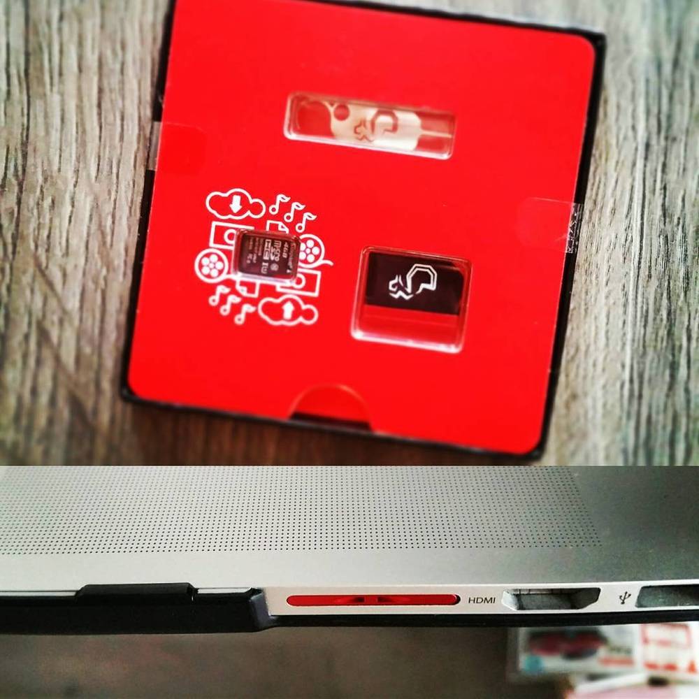 A red retro-style speaker or radio device with icons for music and photos, next to a laptop edge.