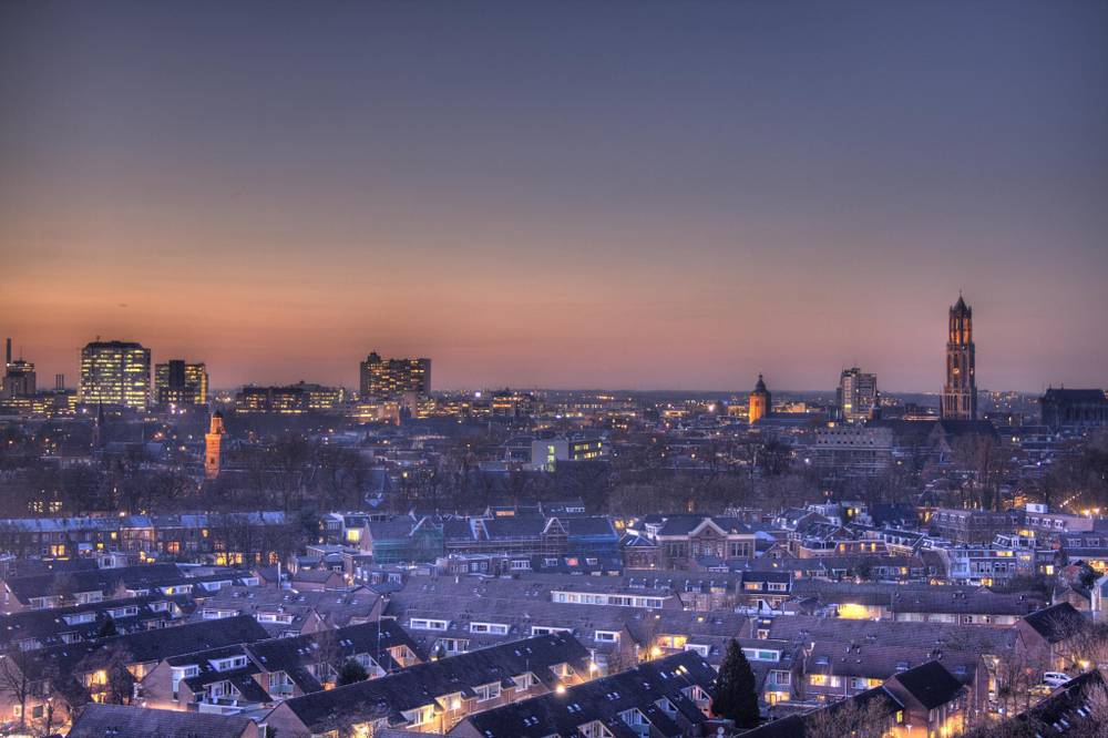 A city skyline at dusk with the Dom Tower silhouetted against a pink sky.