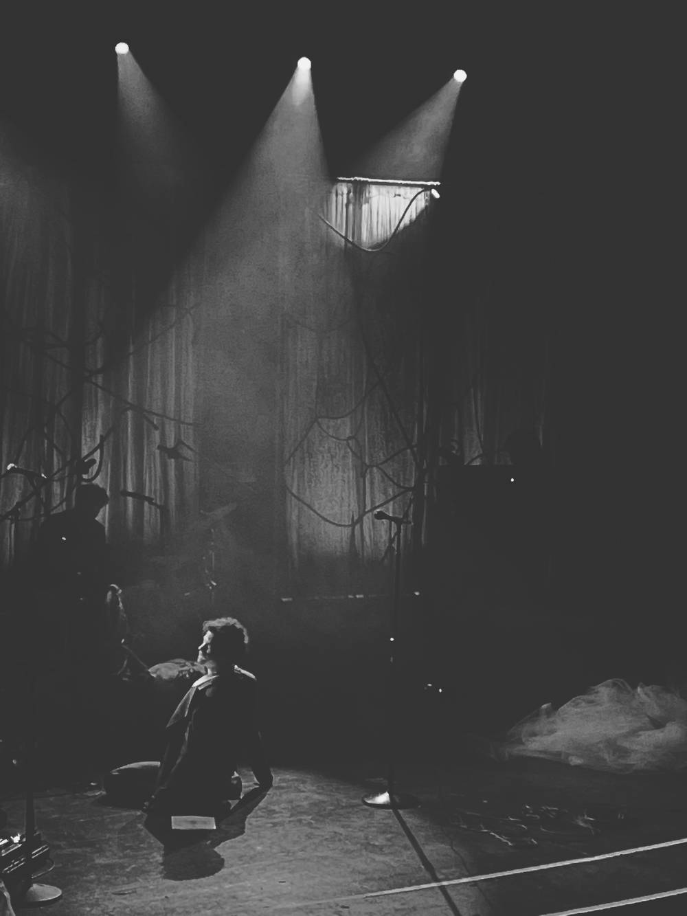A man slowly writhing on the ground, singing.