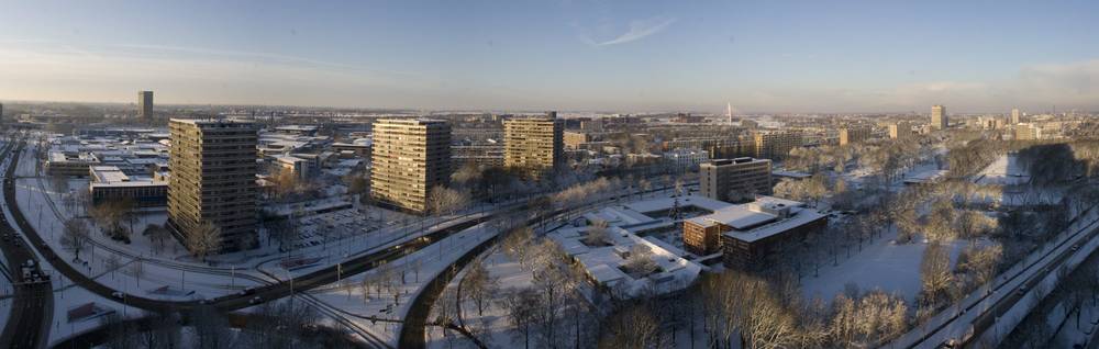 A wide panorama of snow-covered apartment blocks and a frozen canal in the early morning light.