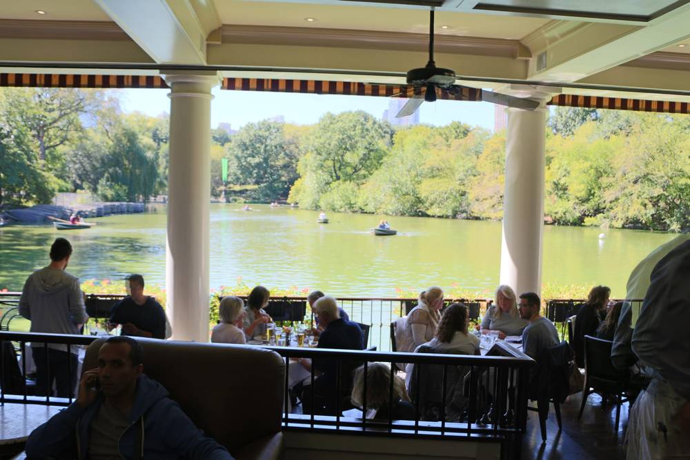 Diners sit beneath a terrace overlooking rowboats on the Central Park lake.