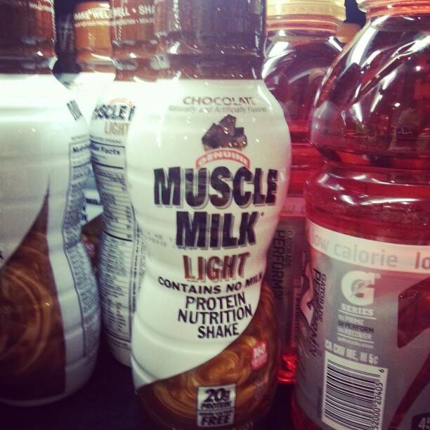 Bottles of Muscle Milk Light protein shake and a Gatorade bottle on a shelf.