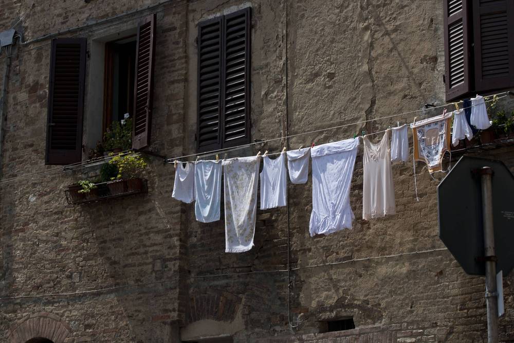 White laundry hangs on a line strung between shuttered windows of a Siena building.
