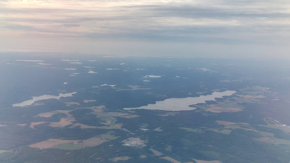 A hazy aerial view over lakes and farmland from an airplane.