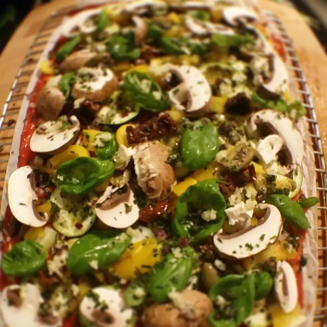 Close-up of a pizza topped with mushrooms, basil and melted cheese.