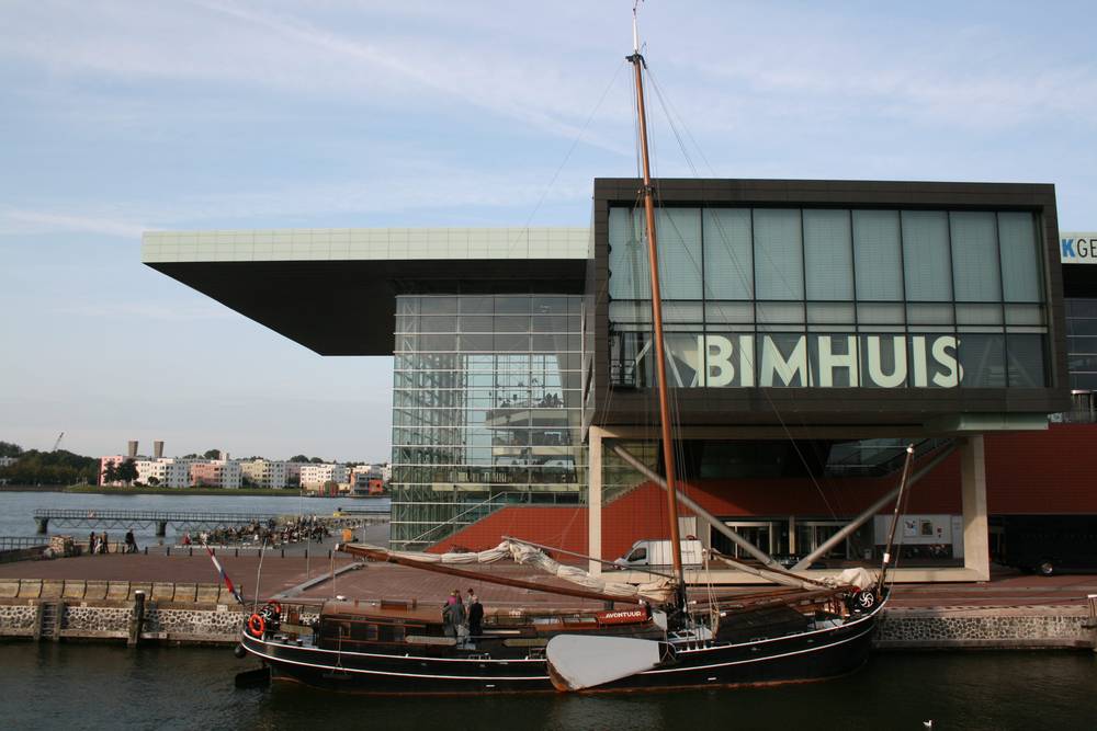 A traditional wooden sailing barge moored beside the Muziekgebouw aan 't IJ concert hall in Amsterdam.