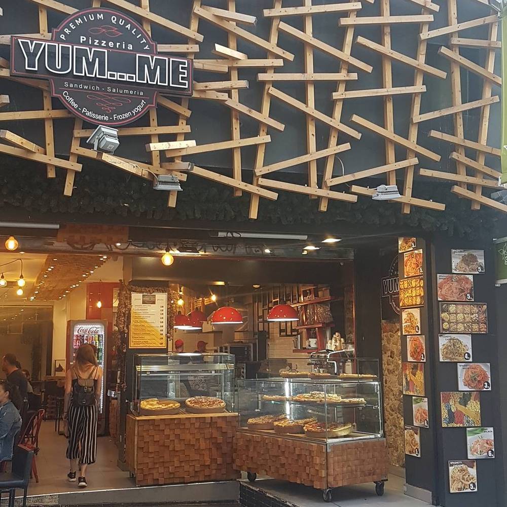 The interior of a sandwich and deli shop called "Yum...me," with pastries in a display case.