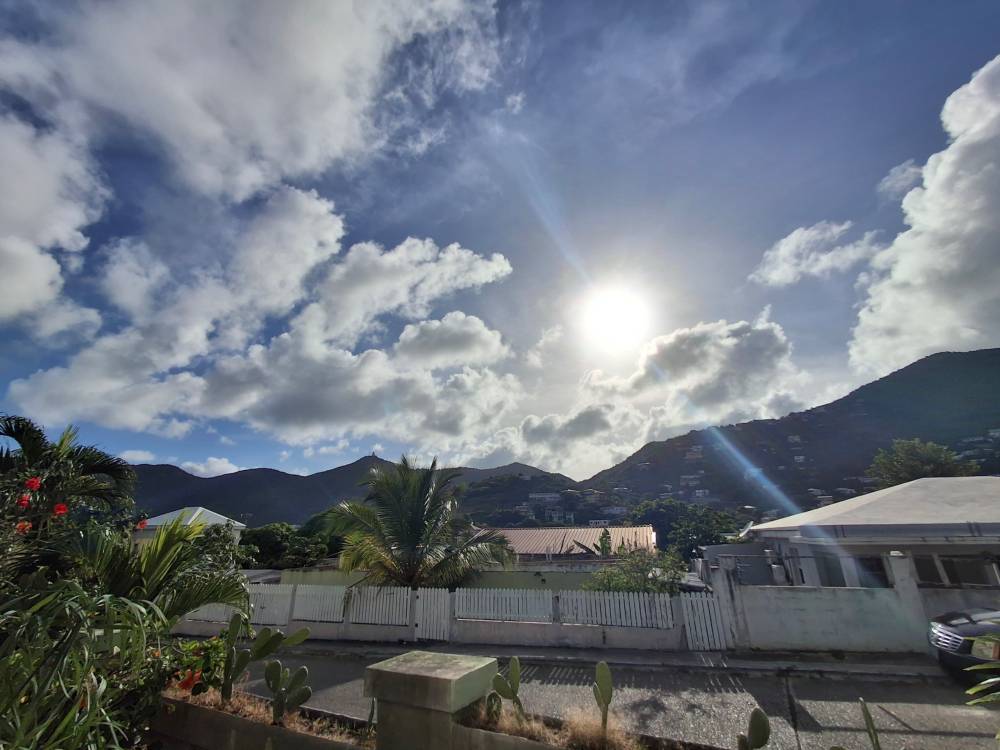 sun shining  in blue skies over Caribbean hilltops. go vegan. 
