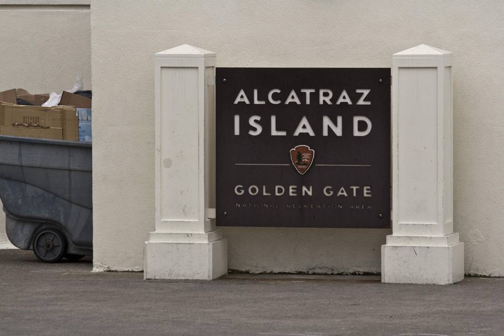 A sign reading 'Alcatraz Island, Golden Gate National Recreation Area' stands by a cart.