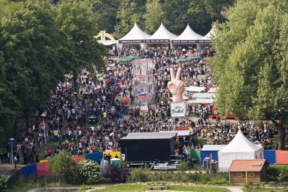 An aerial view shows a huge festival crowd gathered around a stage in a park.