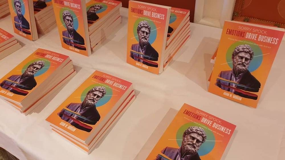 Stacked copies of the book "Sorry Spock: Emotions Drive Business" displayed on a table.