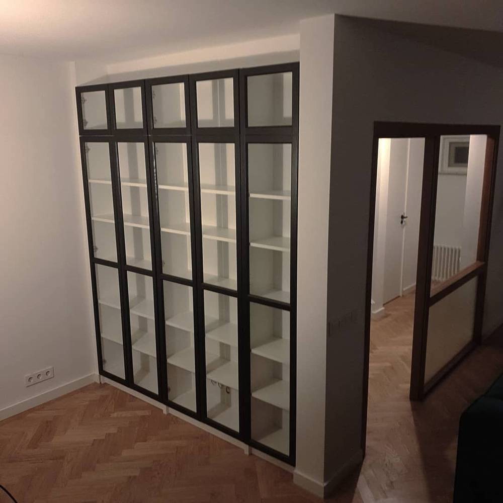 An empty room with a built-in glass-paneled black closet and wood flooring.