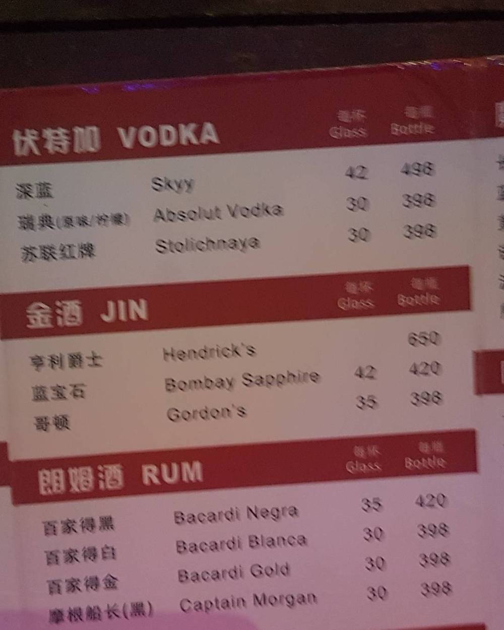 A bar drinks menu listing vodka, gin and rum brands with prices in Chinese and English.