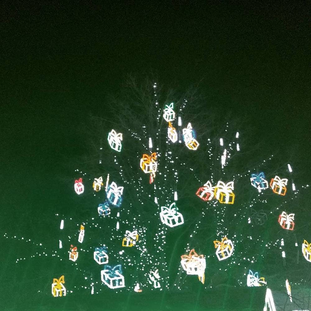 Illuminated Christmas gift-shaped lanterns hanging outdoors at night.