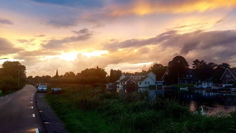 A colorful sunset over a small Dutch village of houses along a waterway.