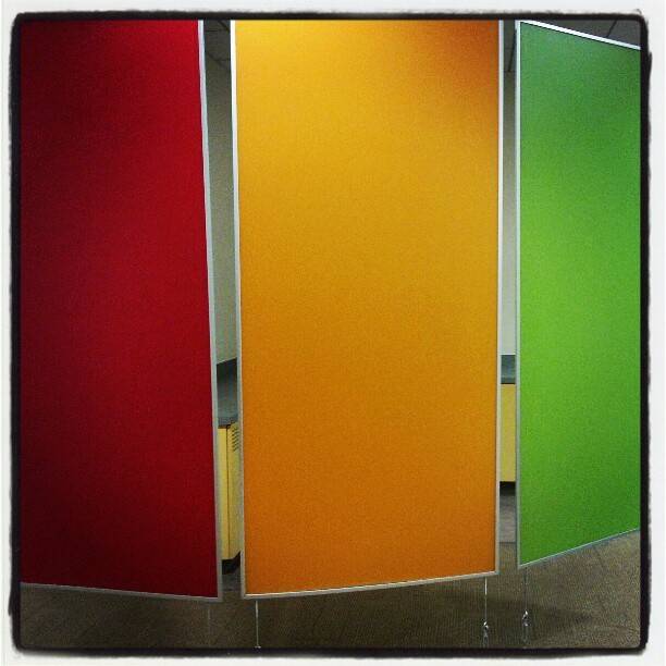 Three brightly colored restroom stall doors in red, orange and green.