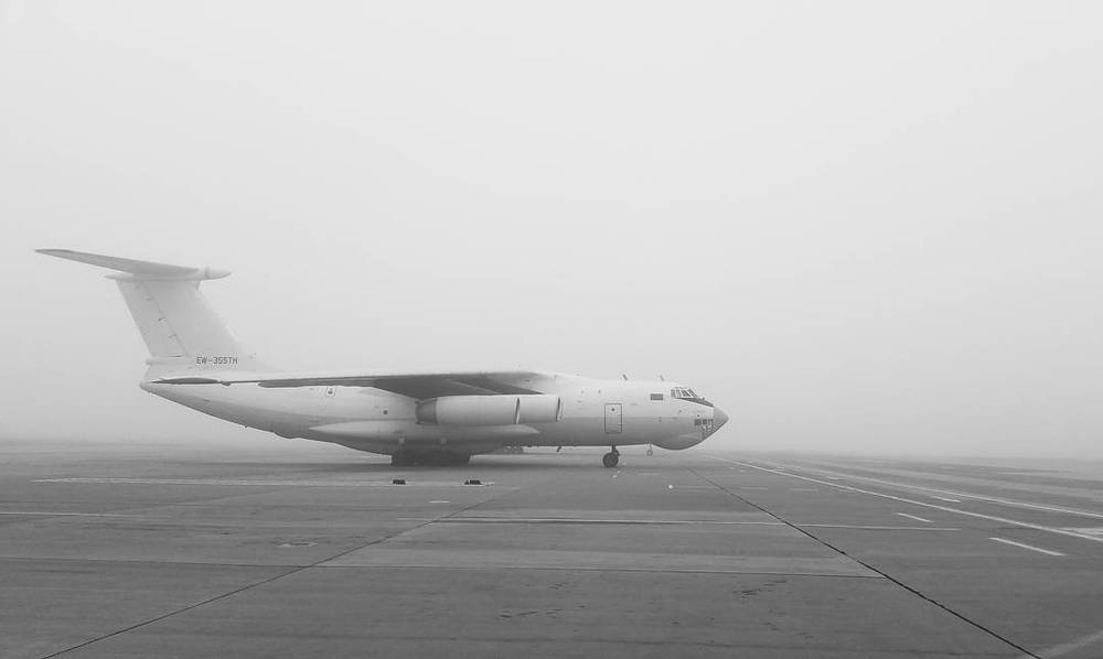 A black and white photo of a large cargo plane on a foggy runway.