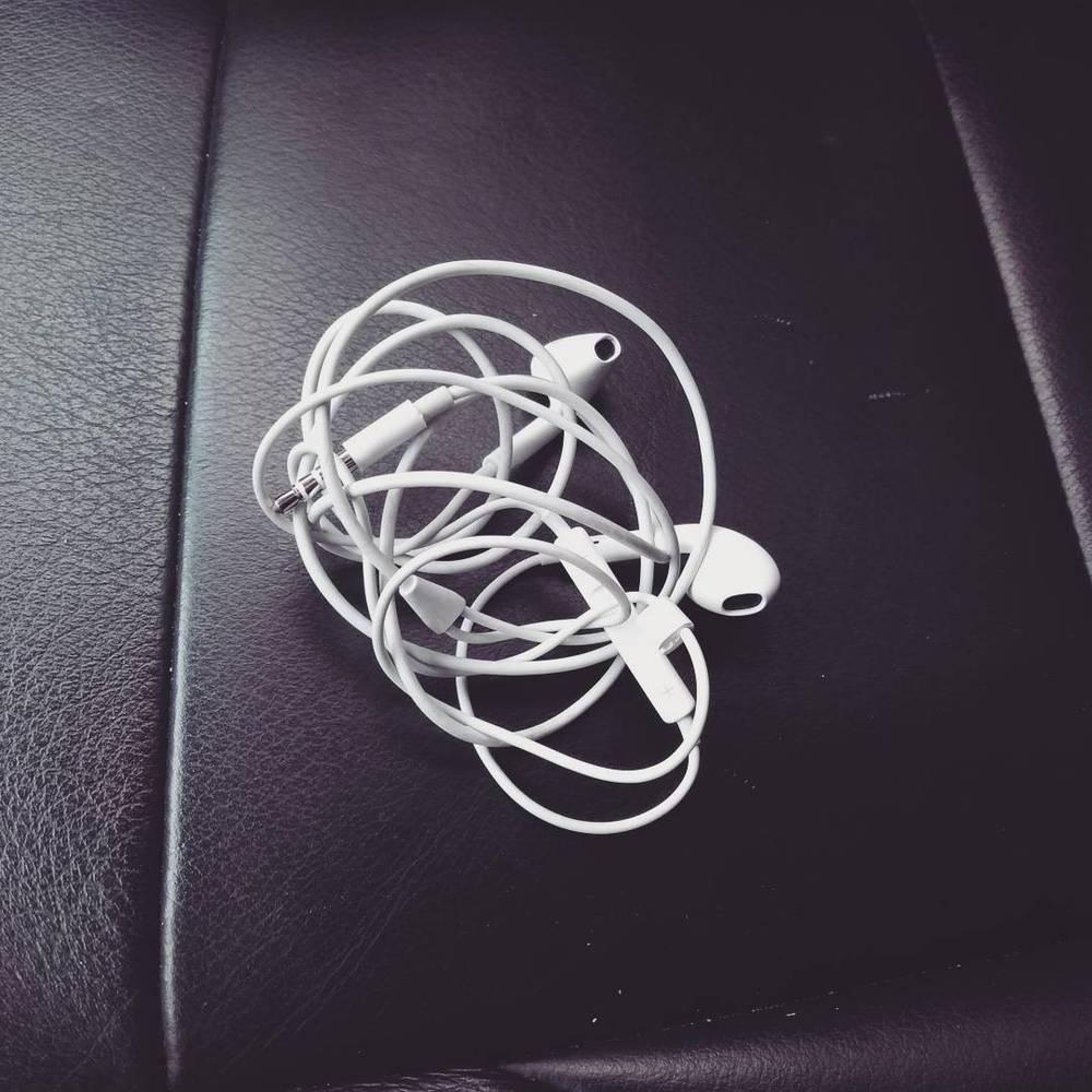 Tangled white earphone cables on a car seat.