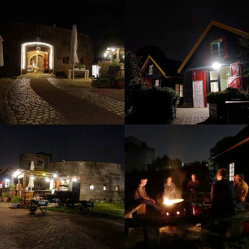 A collage of a fort venue at night: a lit archway gate, cabins, and people gathered around a campfire.