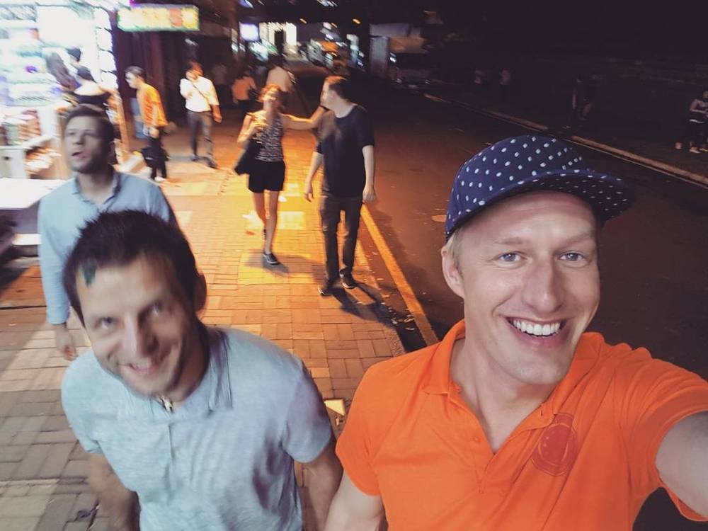 Selfie with a colleague on a busy waterfront promenade in Hong Kong at night.