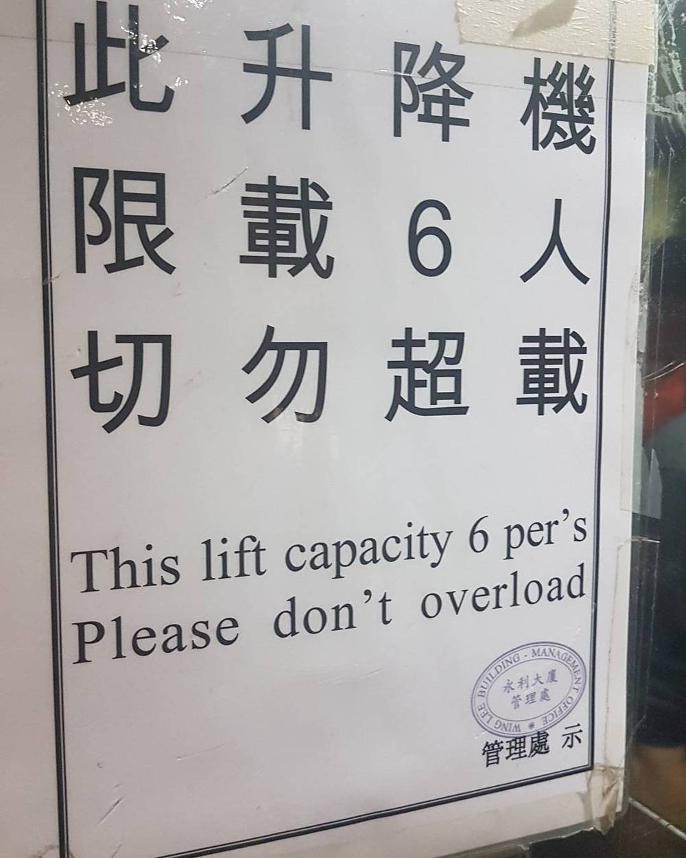 A sign in Chinese and English reading "This lift capacity 6 persons. Please don't overload."