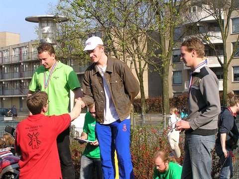 Three young men with medals stand together near an apartment block after a swim meet.