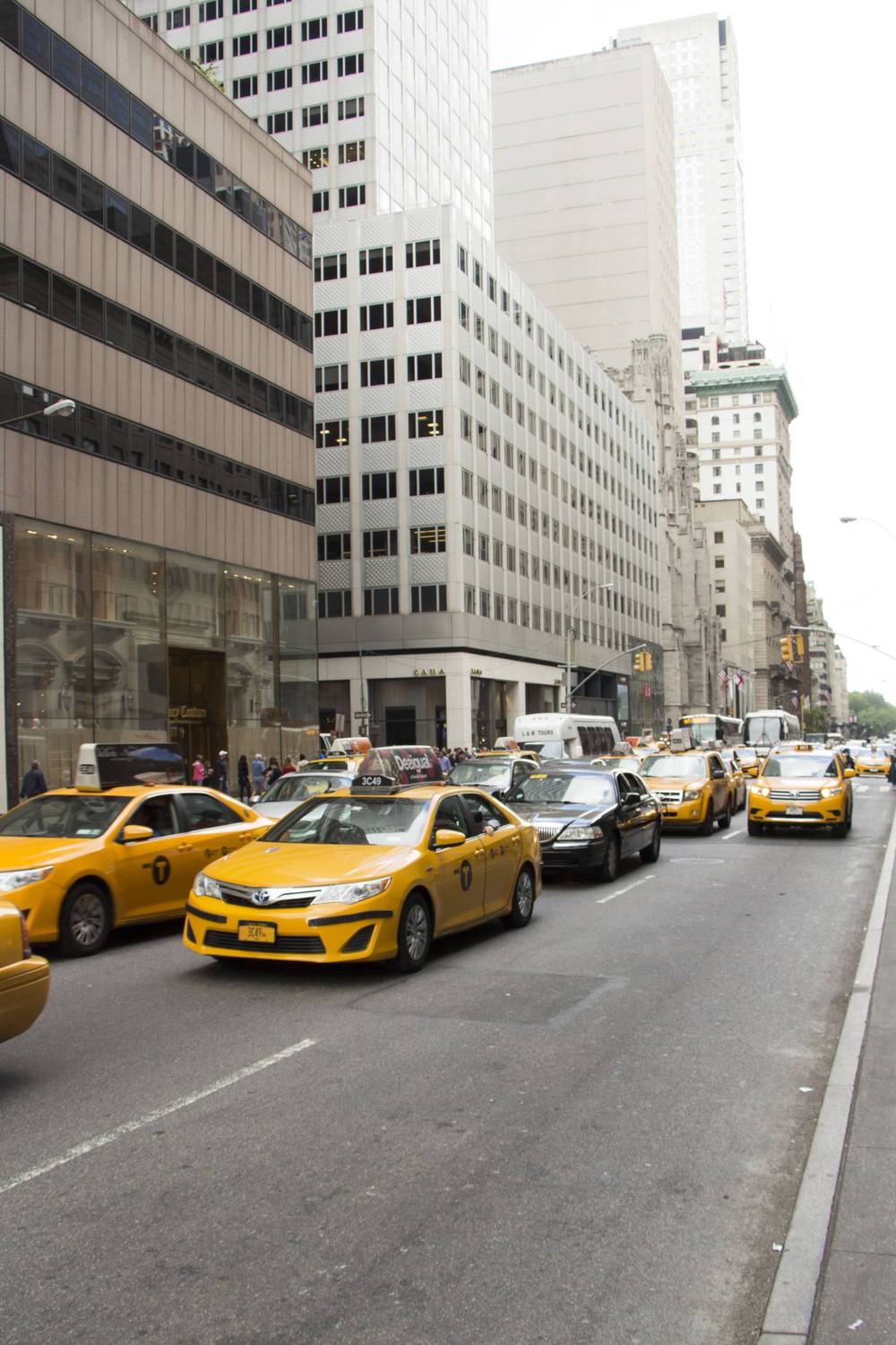 Yellow taxis line a busy Fifth Avenue street.
