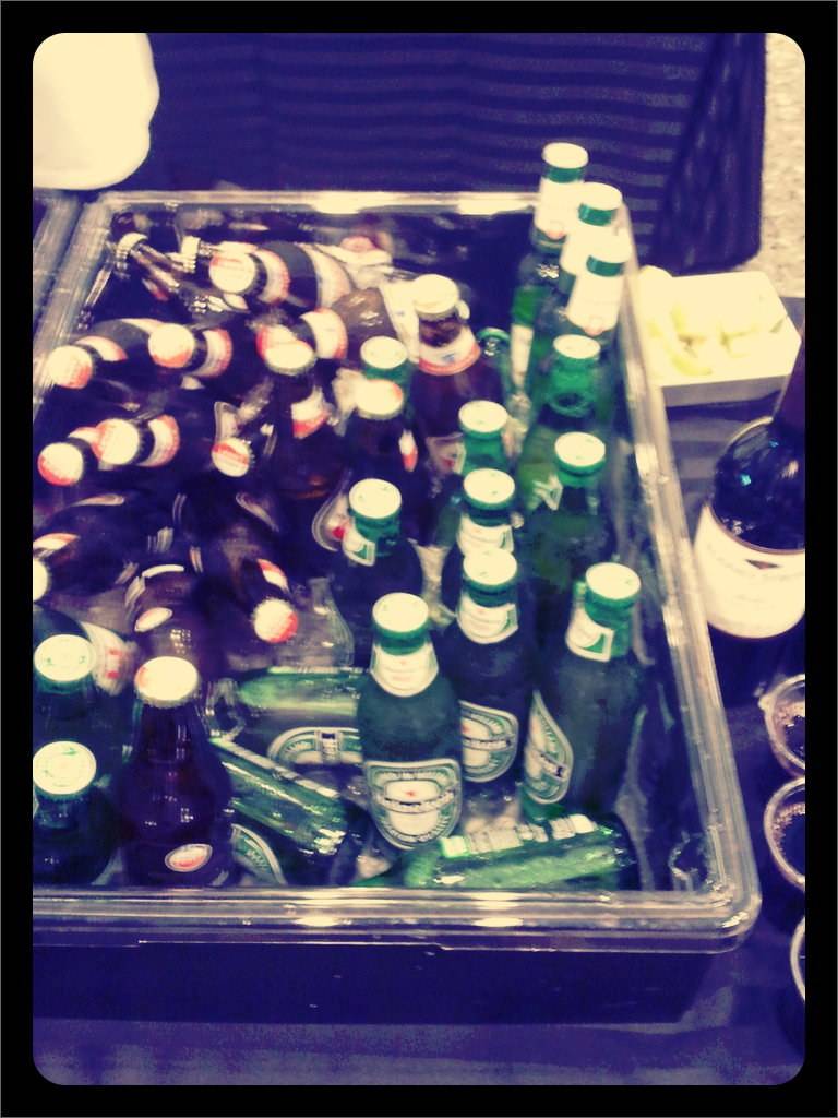 Empty green beer bottles are piled together in a tray at the after-party.