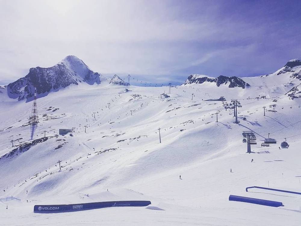A panoramic view of a ski slope with chairlifts running up a snow-covered mountain.