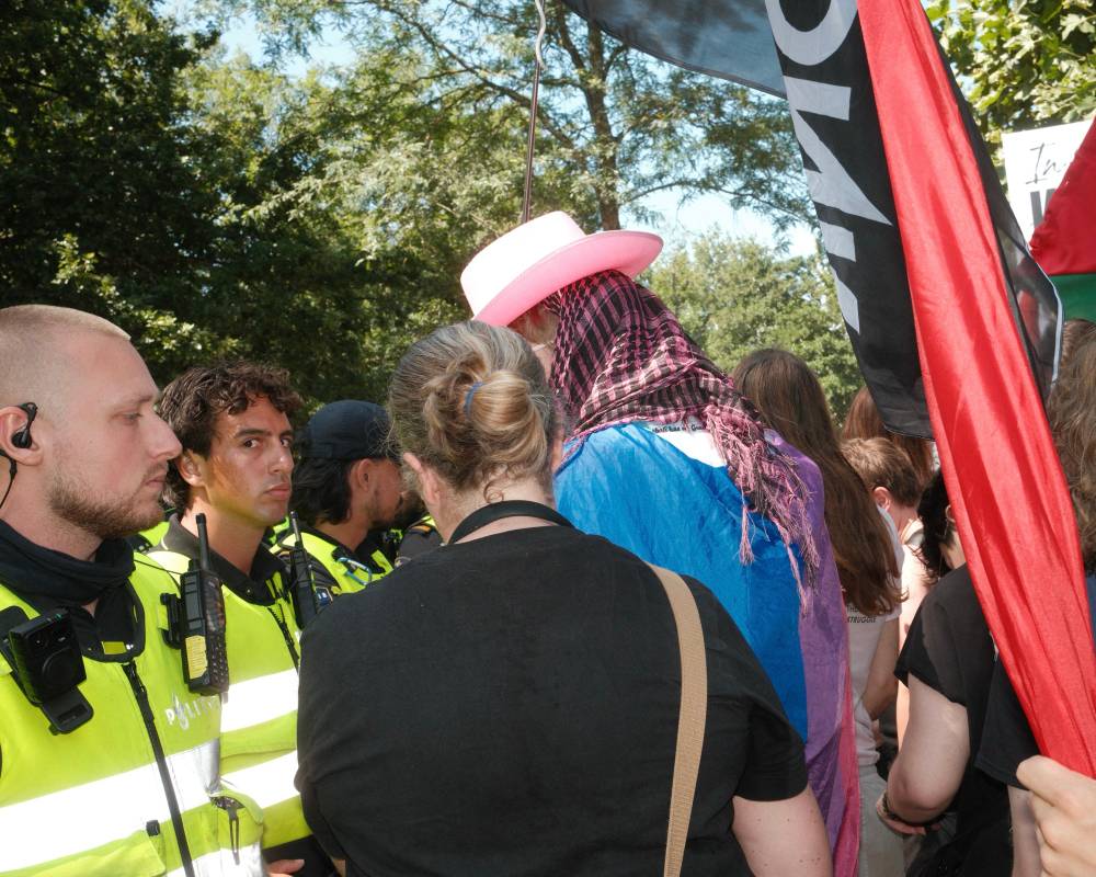 Police man looking at the camera with a side eye in front of protestors