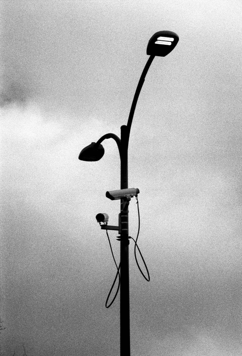 grainy b&w image of security cameras on a light pole